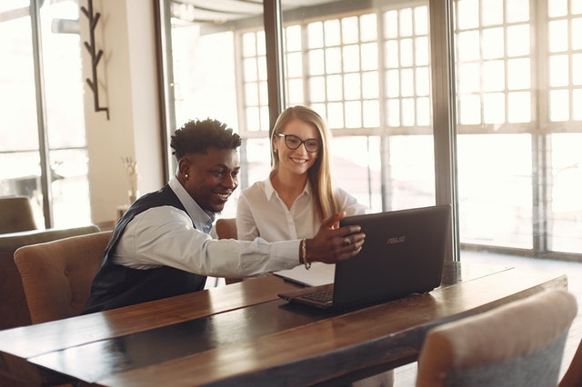 Imagem mostra duas pessoas conversando e olhando em um computador e escolhendo as melhores profissões para dar dinheiro no futuro