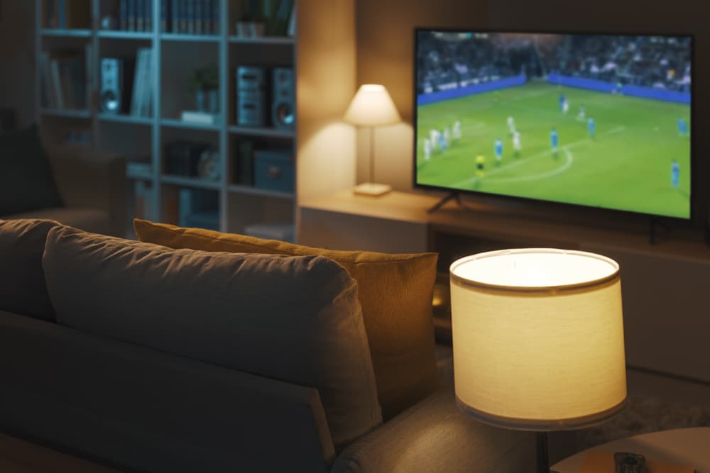 Imagem mostra uma sala de televisão com o futemax passando na televisão